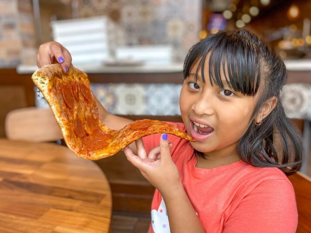 Little girl eating giant pizza slice at Russo's