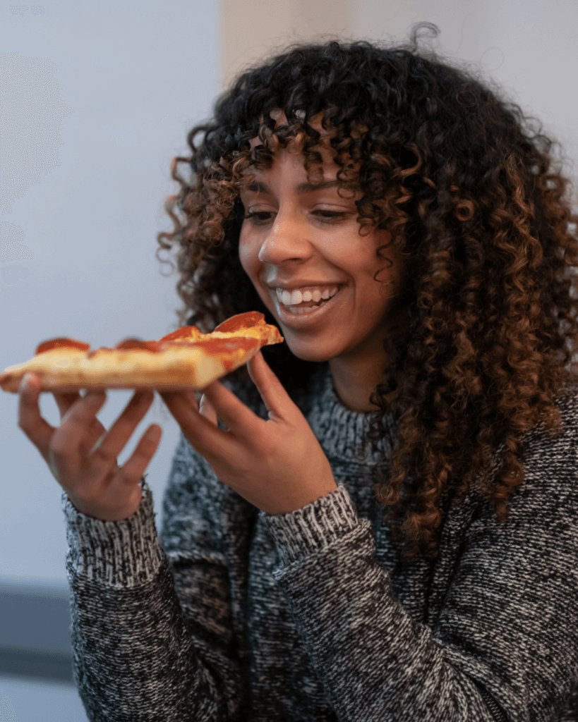 Happy woman eating pizza slice